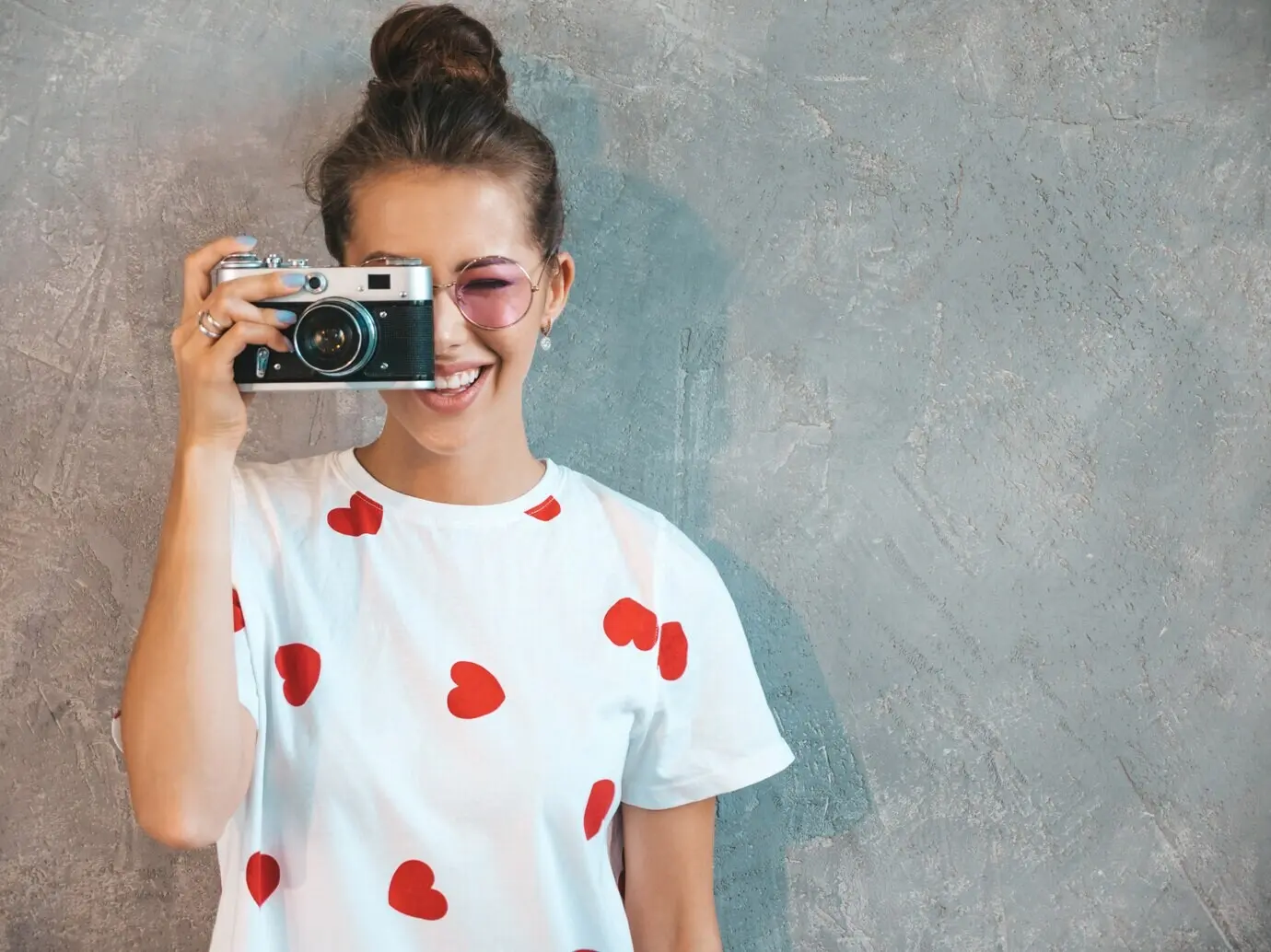 Ein schönes, junges, lächelndes Mädchen, das mit ihrer Retro-Kamera fotografiert.