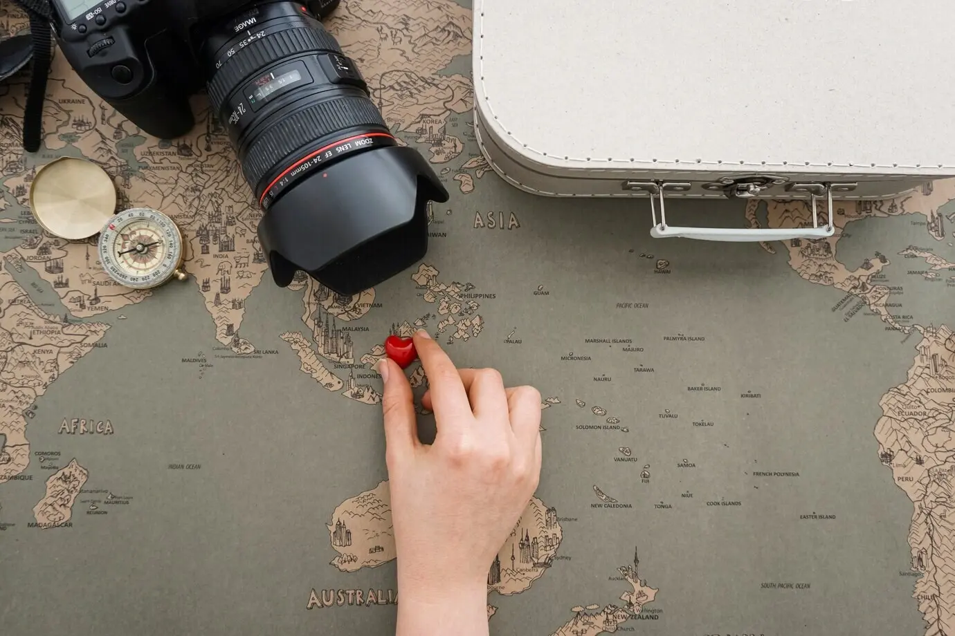 Großartiger Hintergrund mit Reisegegenständen und einer Hand, die ein Herz platziert.