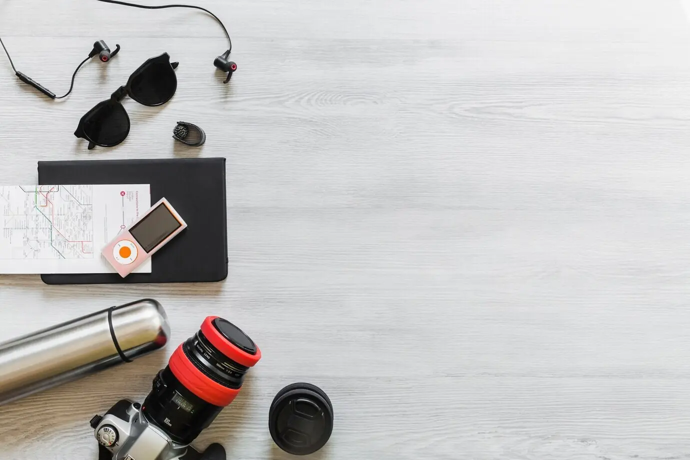 Draufsicht auf diverses Reise-Equipment auf einem Holzschreibtisch.